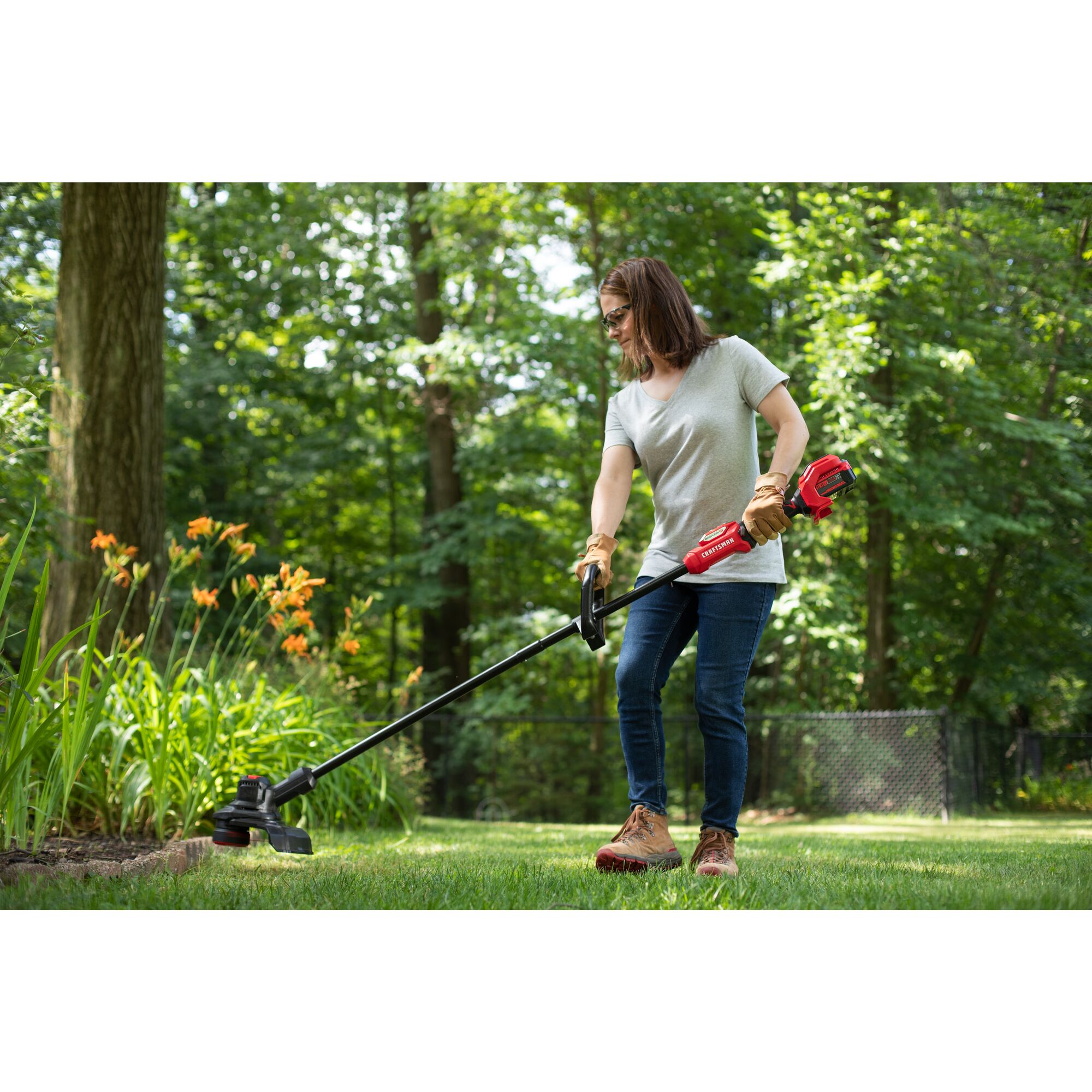 CRAFTSMAN V20 BRUSHLES PR String Trimmer trimming around flowerbed with trees in background